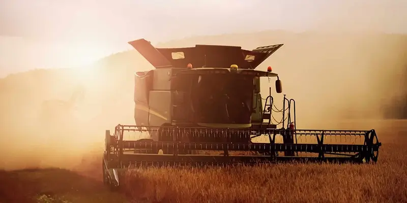 Combine harvester plowing fields at dusk