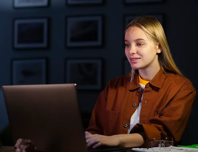 Woman with blonde hair smirking while typing on laptop