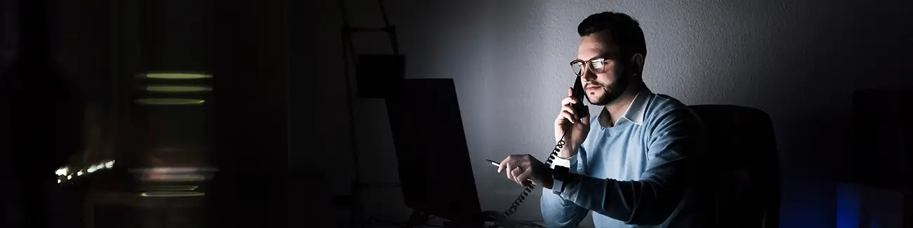 Cyber security expert with glasses pointing at computer monitor