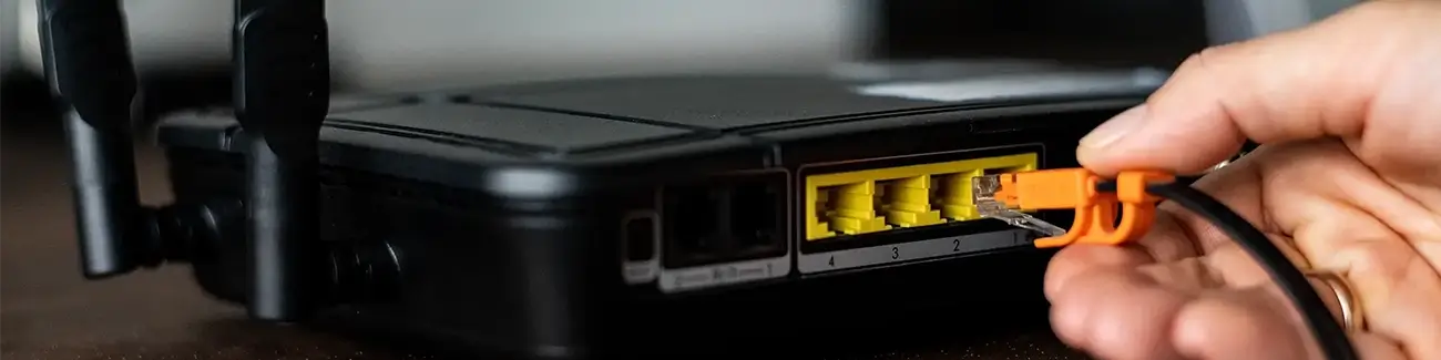 Man putting ethernet cable into back of router