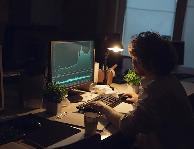 Man in dark room looking at computer monitor