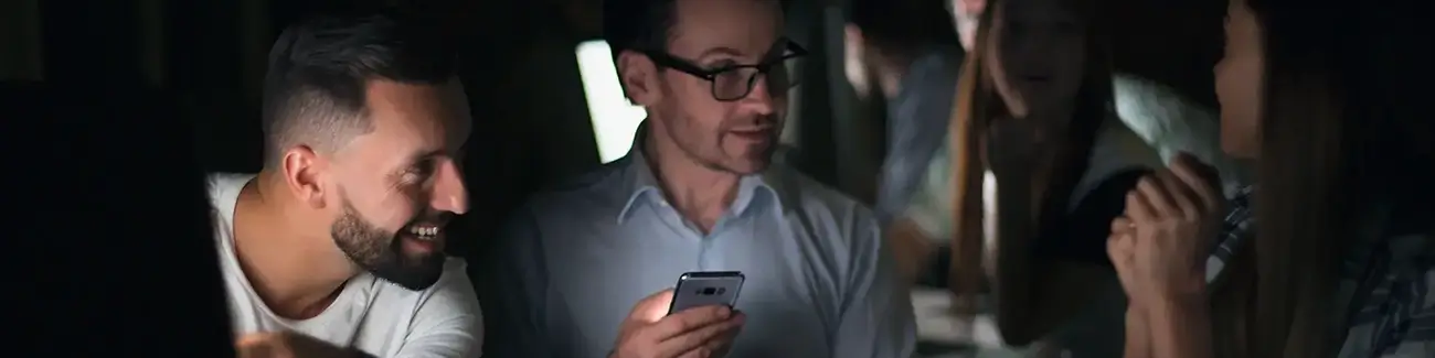 Man with glasses holding phone while woman looks on