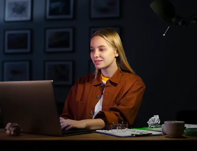 Blonde woman smiling while typing on laptop