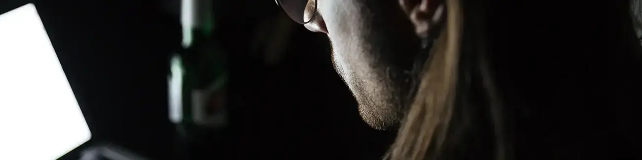 Close-up view of man with glasses looking down at laptop