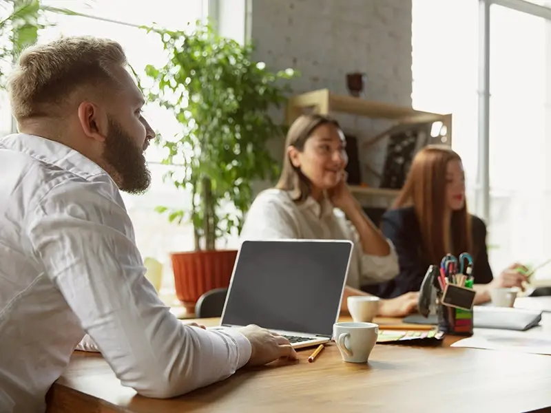 Three employees having a discussion in a break room