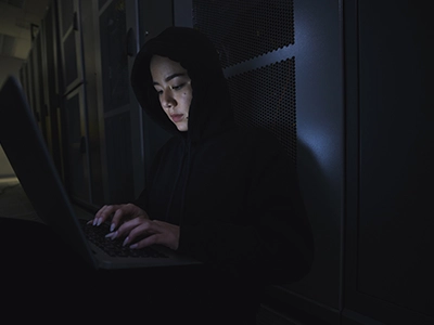 Woman typing on laptop in dark room